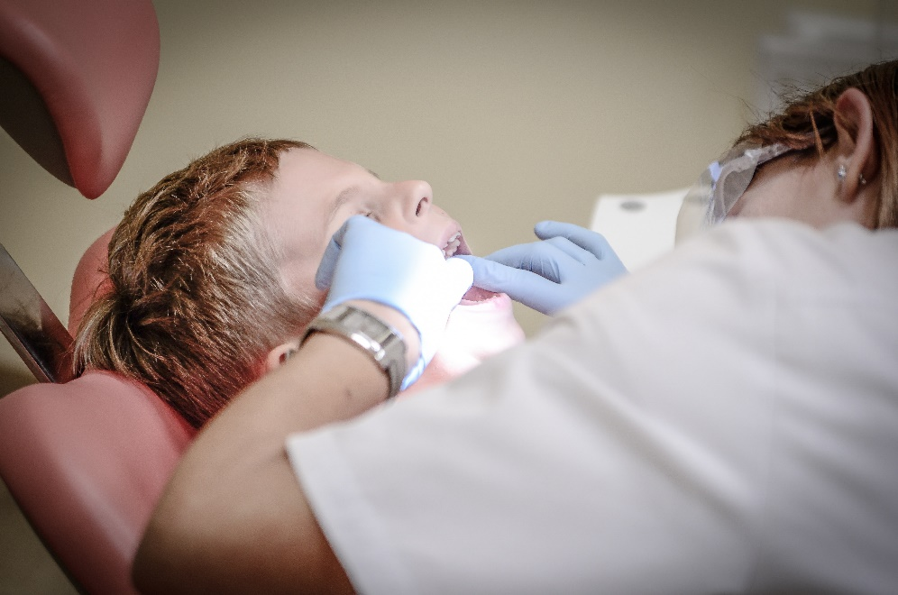 A dentist inspecting a child’s teeth