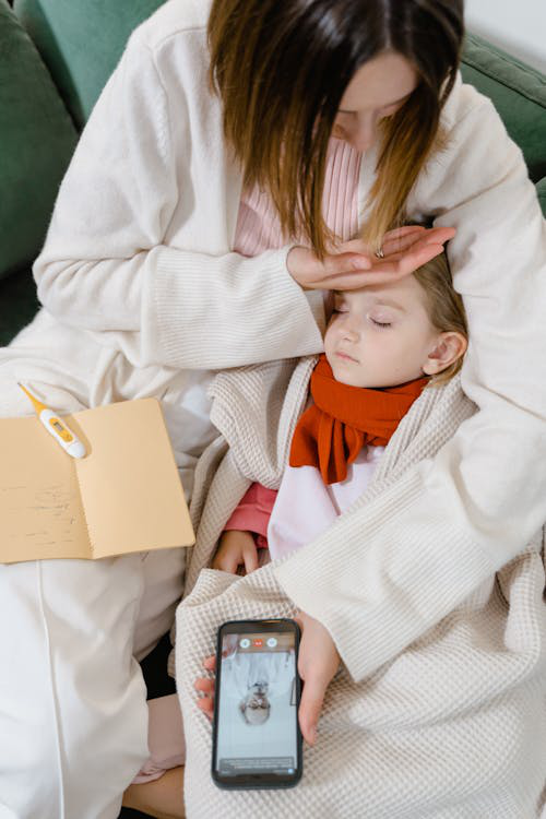 A mother with her sick daughter having an online medical consultation on her mobile phone